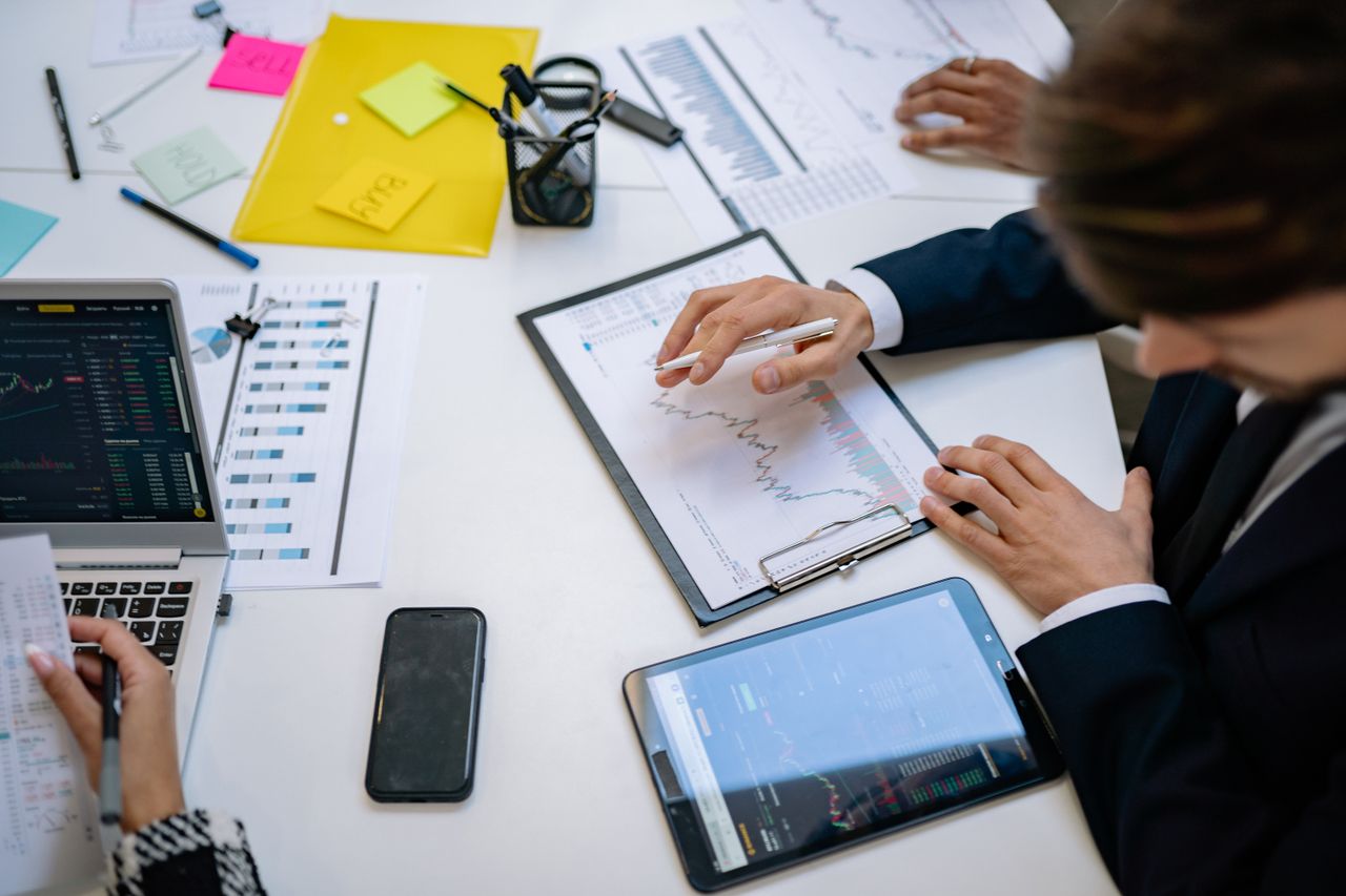 A team in an office reviewing financial charts and digital data on tablets.
